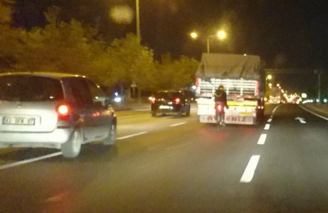 Tehlikeye aldırış etmeden bisikletiyle kamyonun arkasında seyretti